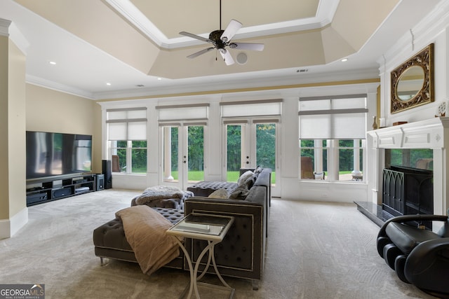 living room featuring a premium fireplace, carpet, ceiling fan, a raised ceiling, and crown molding