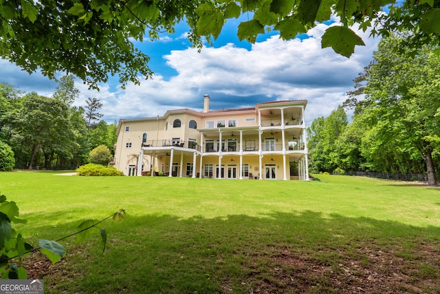 back of property featuring a balcony and a lawn