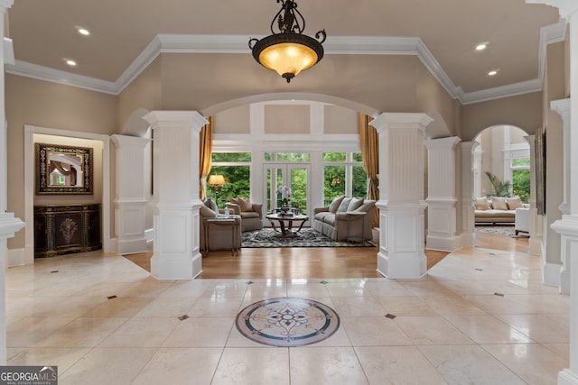 foyer entrance featuring ornamental molding, decorative columns, and light wood-type flooring