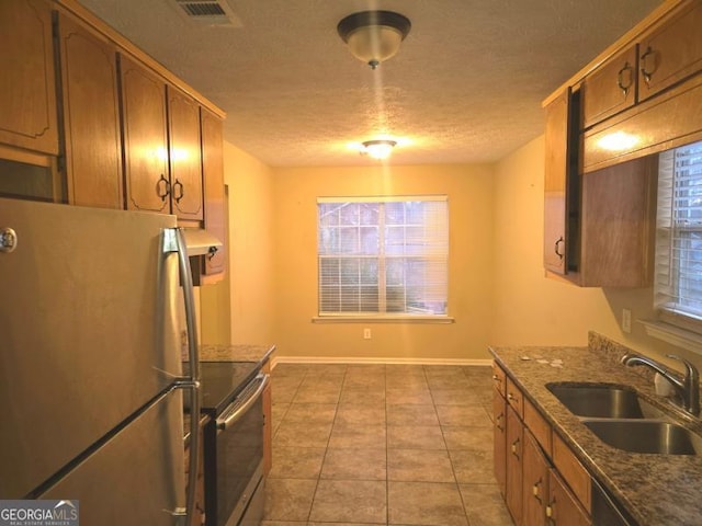 kitchen with electric stove, sink, light tile patterned floors, refrigerator, and a textured ceiling