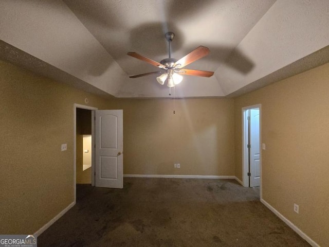 unfurnished bedroom with a raised ceiling, dark colored carpet, and lofted ceiling