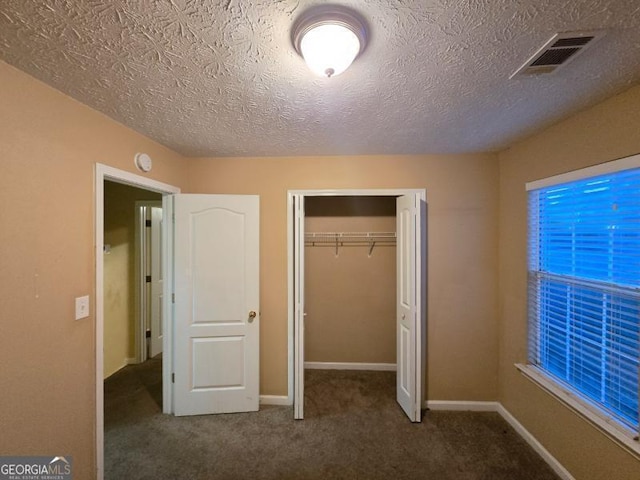 unfurnished bedroom with dark colored carpet and a closet