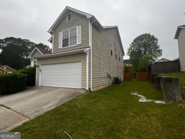 view of property exterior with a garage, a yard, and central air condition unit