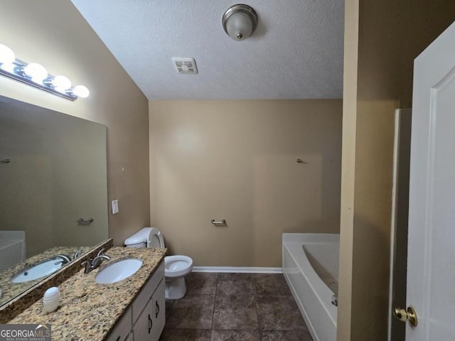 bathroom with vanity, toilet, a bathtub, and a textured ceiling