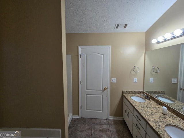 bathroom with tile patterned floors, vanity, and a textured ceiling