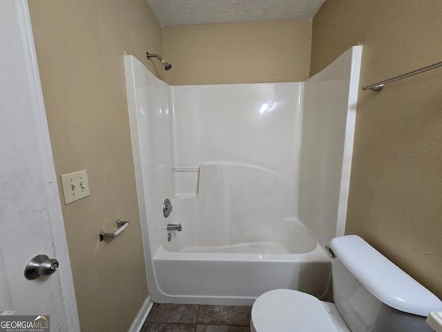 bathroom featuring tile patterned flooring, bathing tub / shower combination, a textured ceiling, and toilet