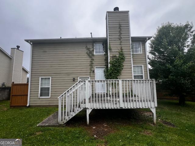 rear view of property featuring a wooden deck and a yard