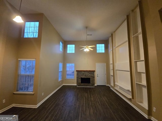 unfurnished living room with ceiling fan, a fireplace, plenty of natural light, and dark hardwood / wood-style floors