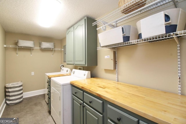 clothes washing area with cabinets, washing machine and dryer, a textured ceiling, and hookup for a washing machine