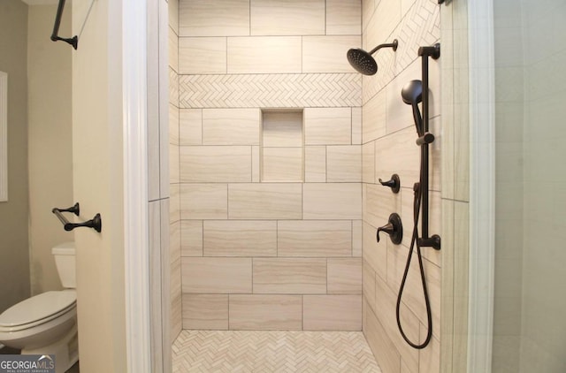 bathroom featuring tiled shower and toilet