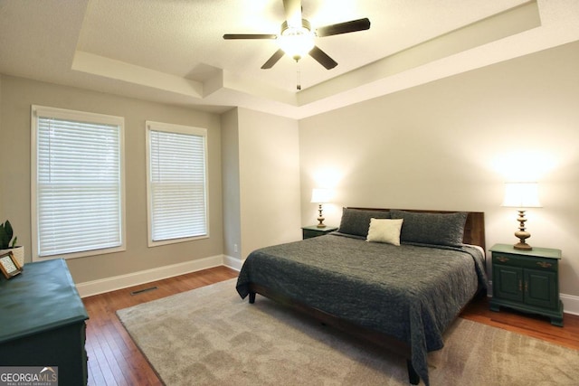 bedroom featuring ceiling fan, a raised ceiling, and hardwood / wood-style flooring