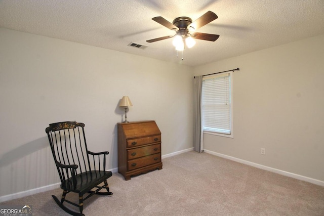 living area with a textured ceiling, carpet floors, and ceiling fan