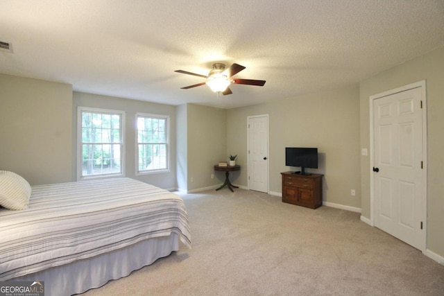 bedroom with ceiling fan, carpet floors, and a textured ceiling