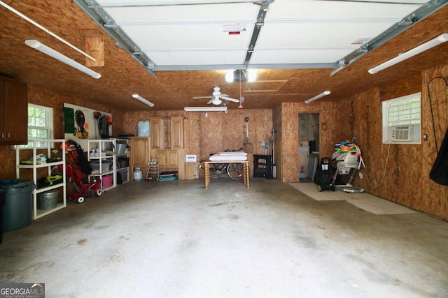 garage featuring wooden walls, ceiling fan, and a garage door opener