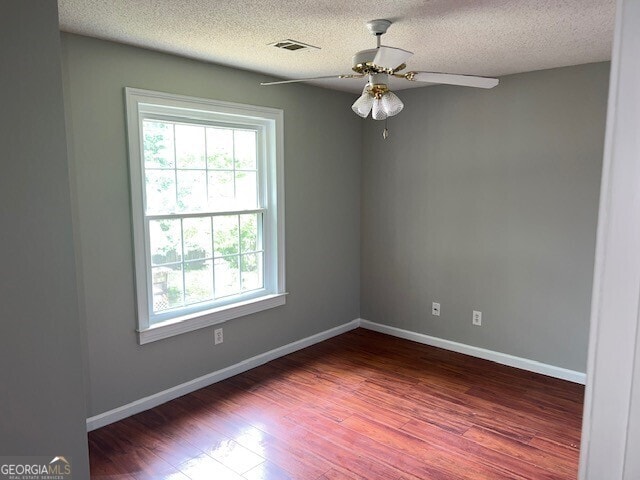 empty room with a textured ceiling, ceiling fan, and dark hardwood / wood-style floors