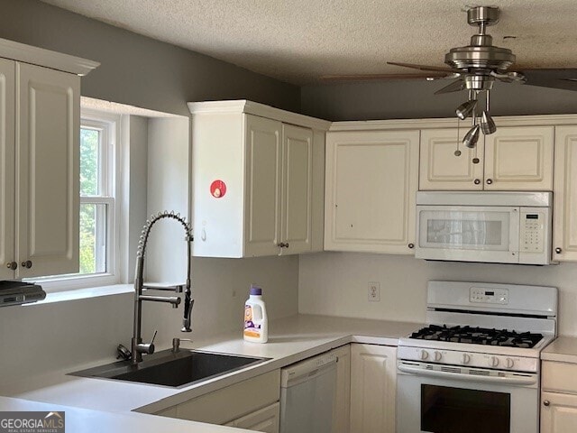 kitchen with white cabinetry, ceiling fan, sink, and white appliances