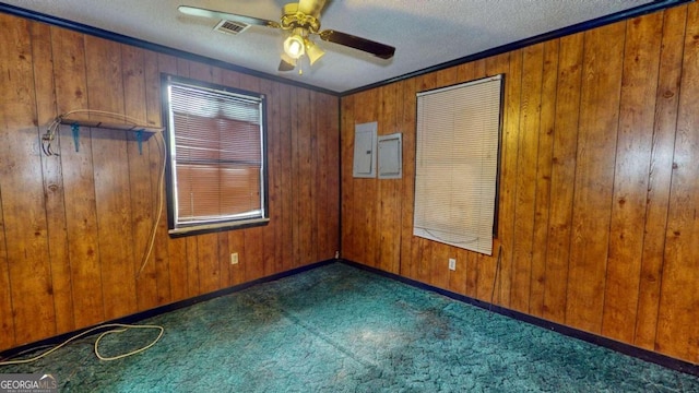 carpeted empty room with wooden walls, ceiling fan, a textured ceiling, and ornamental molding