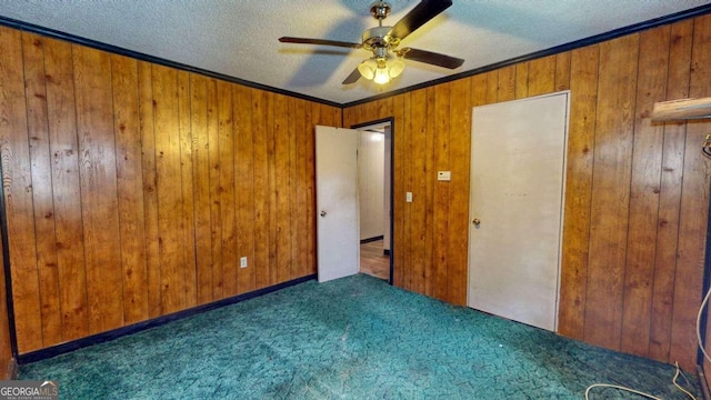 empty room with wooden walls, ceiling fan, a textured ceiling, and dark carpet