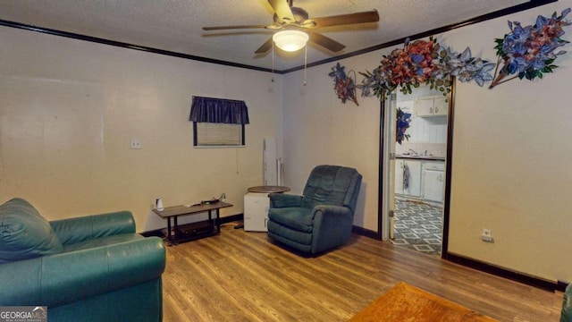 living room featuring hardwood / wood-style floors, ceiling fan, a textured ceiling, and crown molding