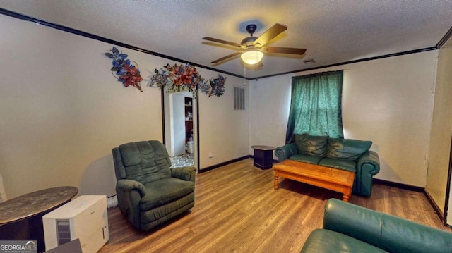 living room featuring crown molding, ceiling fan, a textured ceiling, and wood-type flooring