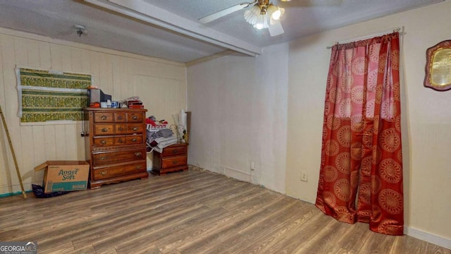 misc room with wood-type flooring, beam ceiling, ceiling fan, and a textured ceiling