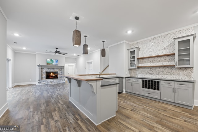 kitchen with gray cabinetry, tasteful backsplash, dark hardwood / wood-style flooring, a fireplace, and ornamental molding