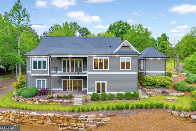 rear view of house with a balcony and an outdoor fire pit