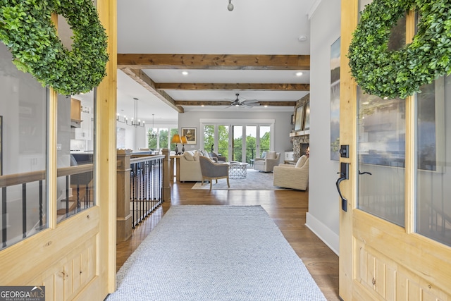 entrance foyer featuring beamed ceiling, a fireplace, dark hardwood / wood-style floors, and ceiling fan