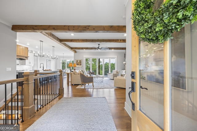 interior space with ceiling fan, crown molding, beamed ceiling, sink, and dark hardwood / wood-style floors