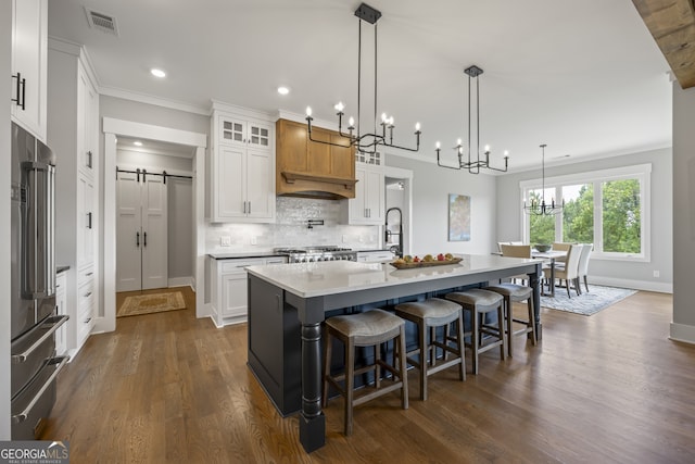 kitchen featuring white cabinets, dark wood-type flooring, decorative backsplash, and an island with sink