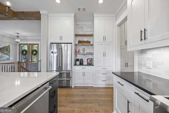 kitchen featuring dark stone counters, white cabinets, stainless steel appliances, dark hardwood / wood-style floors, and decorative backsplash