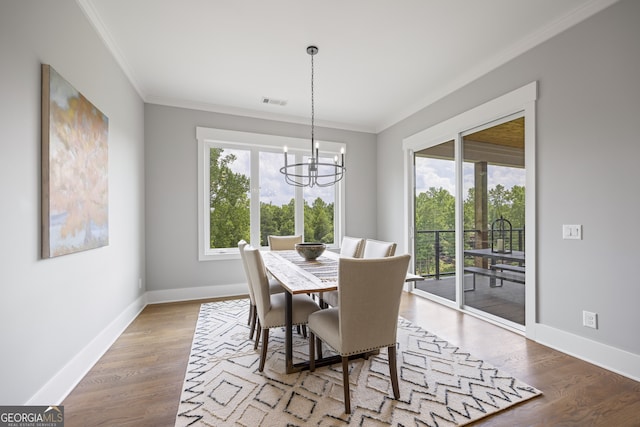 dining space with light hardwood / wood-style floors, crown molding, and an inviting chandelier