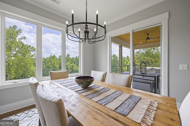 dining area with wood-type flooring, a notable chandelier, ornamental molding, and plenty of natural light