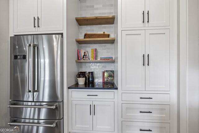 kitchen featuring decorative backsplash, high quality fridge, and white cabinetry