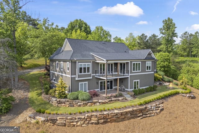 rear view of property featuring a balcony, a lawn, and a patio area