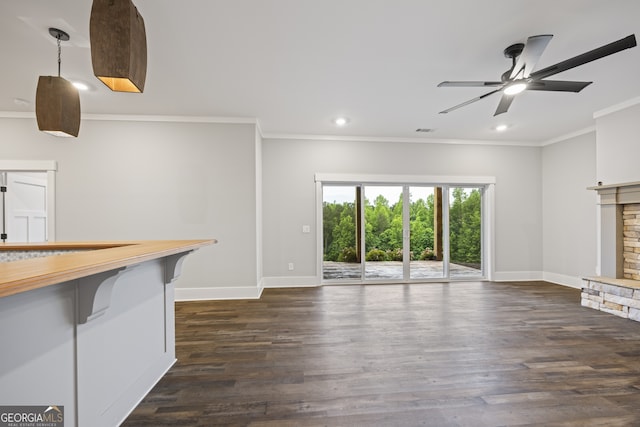 unfurnished living room with dark wood-type flooring, crown molding, a fireplace, and ceiling fan