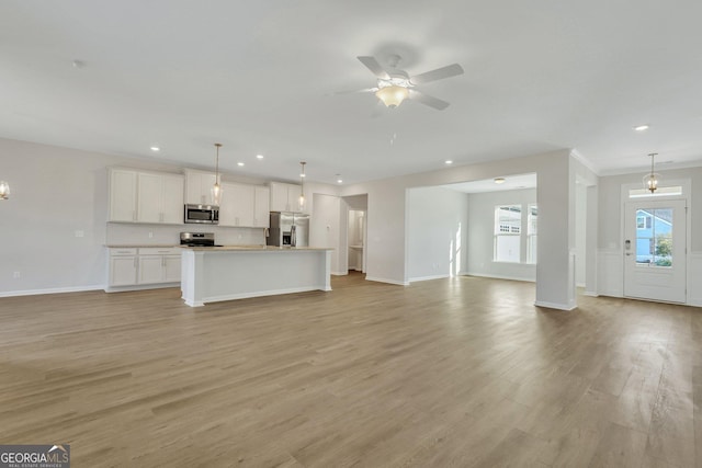 unfurnished living room featuring ceiling fan with notable chandelier and light hardwood / wood-style floors