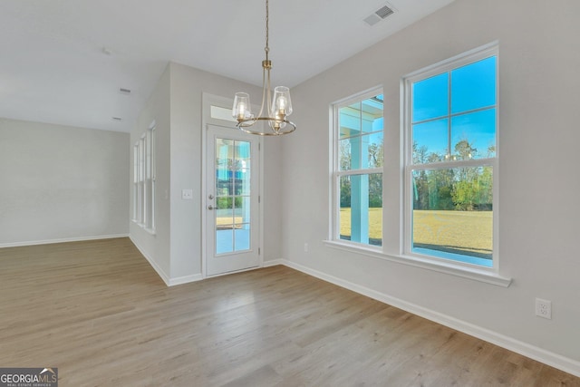 unfurnished dining area with a chandelier and light wood-type flooring