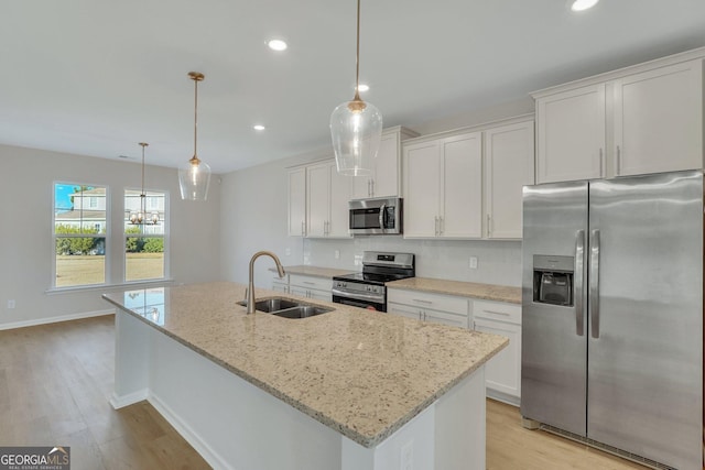 kitchen featuring sink, white cabinetry, a center island with sink, pendant lighting, and stainless steel appliances