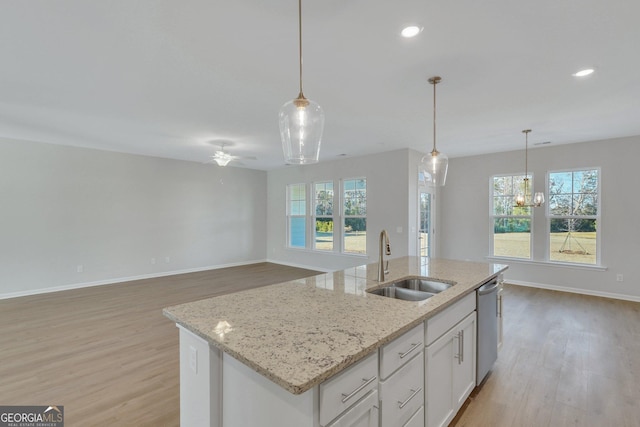 kitchen featuring white cabinetry, sink, a center island with sink, and pendant lighting