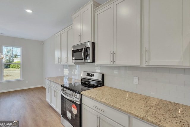 kitchen with light hardwood / wood-style flooring, appliances with stainless steel finishes, white cabinetry, tasteful backsplash, and light stone countertops