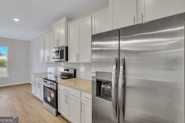 kitchen with light hardwood / wood-style flooring, white cabinetry, backsplash, stainless steel appliances, and light stone counters