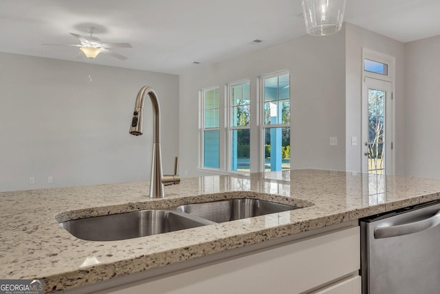 kitchen with light stone counters, stainless steel dishwasher, and sink