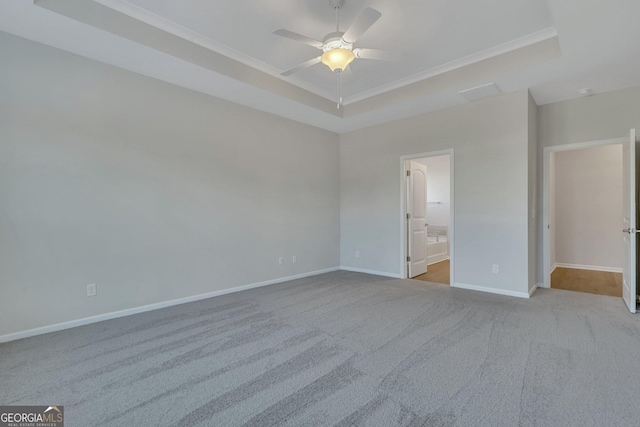 unfurnished bedroom featuring ornamental molding, ceiling fan, a raised ceiling, light carpet, and ensuite bath