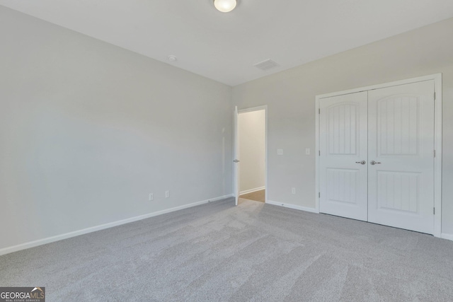 unfurnished bedroom with light carpet and a closet