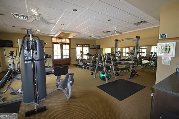 gym featuring ceiling fan, carpet flooring, and a paneled ceiling