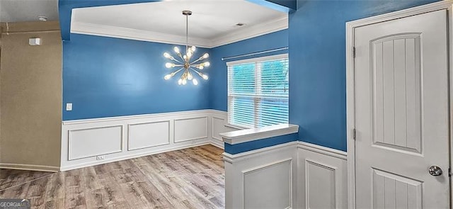 unfurnished dining area with wood-type flooring, a chandelier, and crown molding