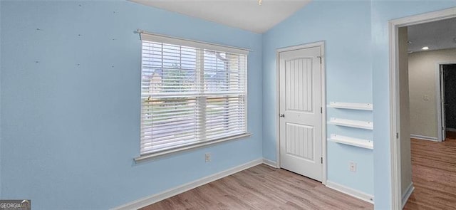 unfurnished bedroom featuring lofted ceiling and light wood-type flooring