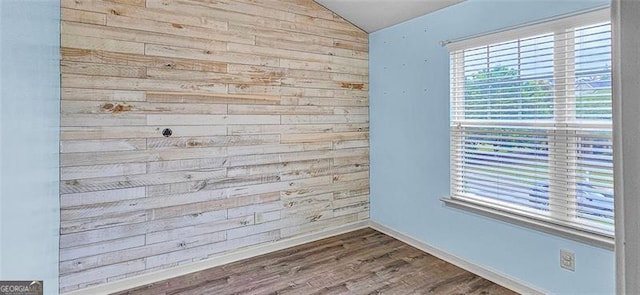 unfurnished room with wood walls, dark hardwood / wood-style floors, and lofted ceiling