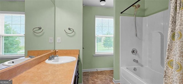 bathroom with shower / bath combination with curtain, a healthy amount of sunlight, and vanity with extensive cabinet space